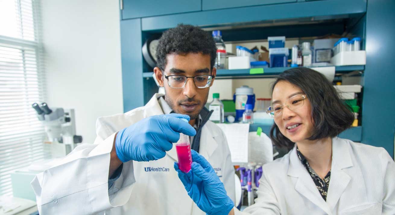 students in white coats working in lab