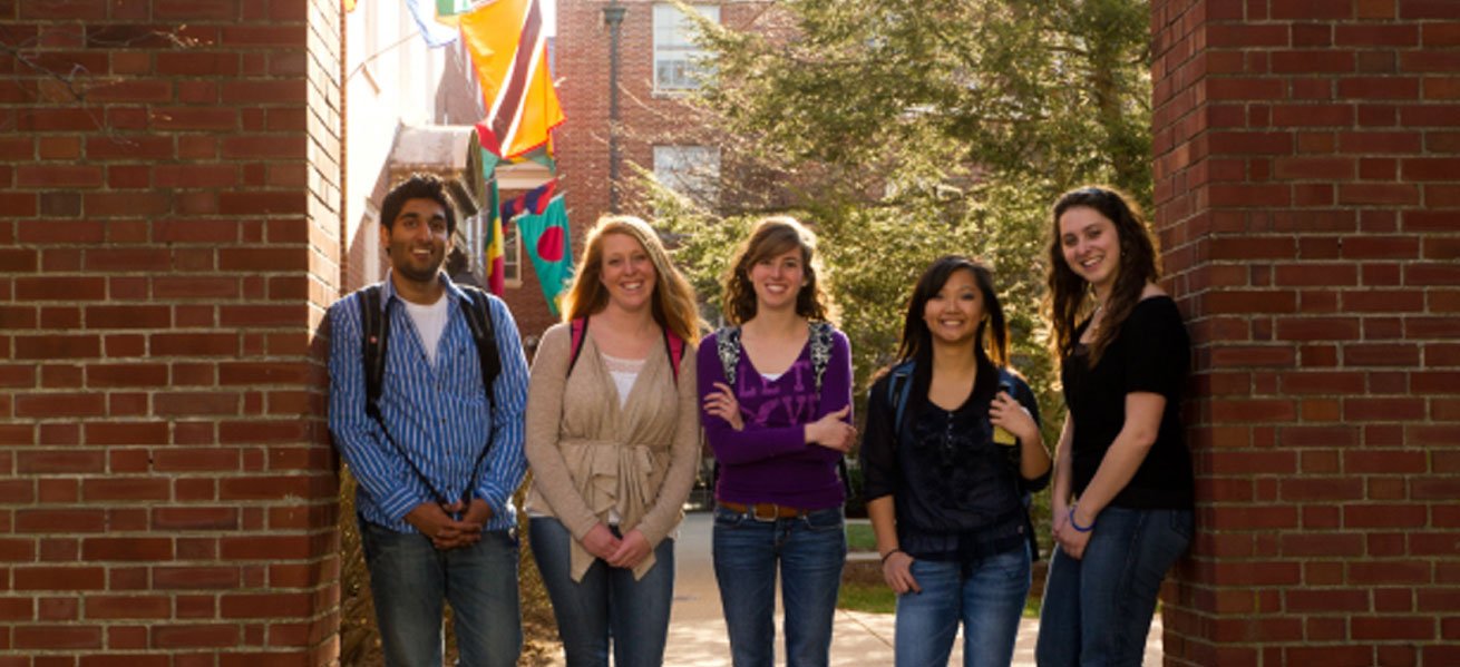 diverse group of students with backpacks by a brick building
