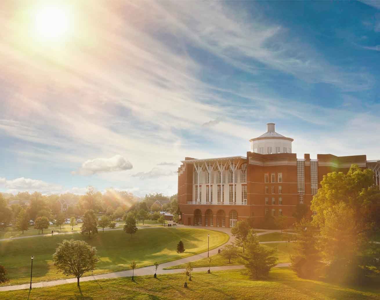 large brick building and green grounds at sunrise