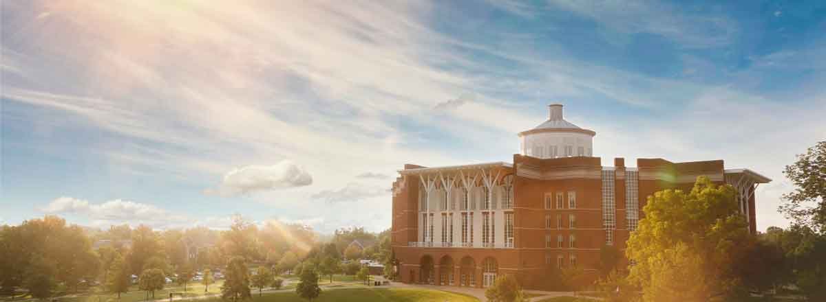 large brick building and green grounds at sunrise