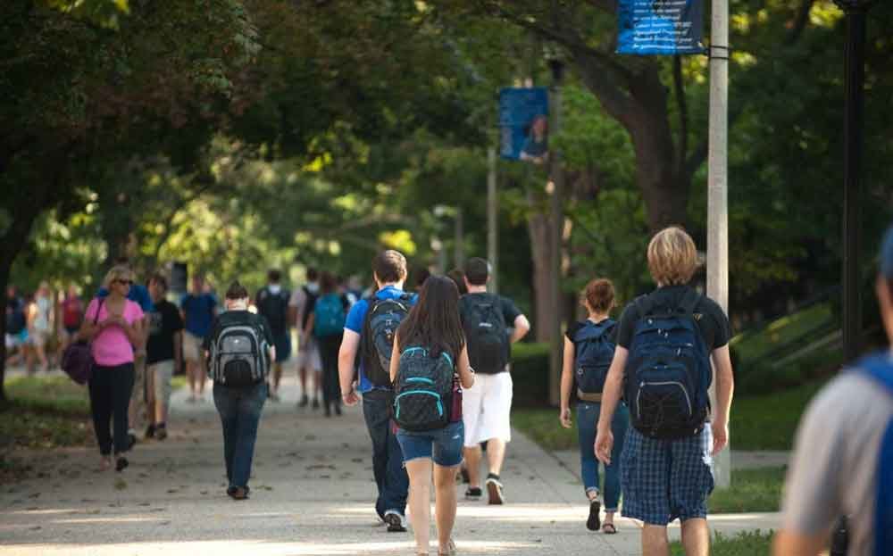 students with backpacks fill walkways on campus