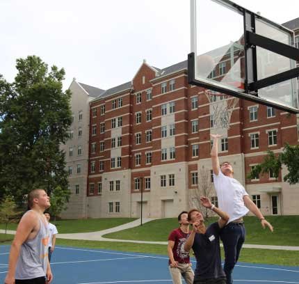 male students playing basketball on campus