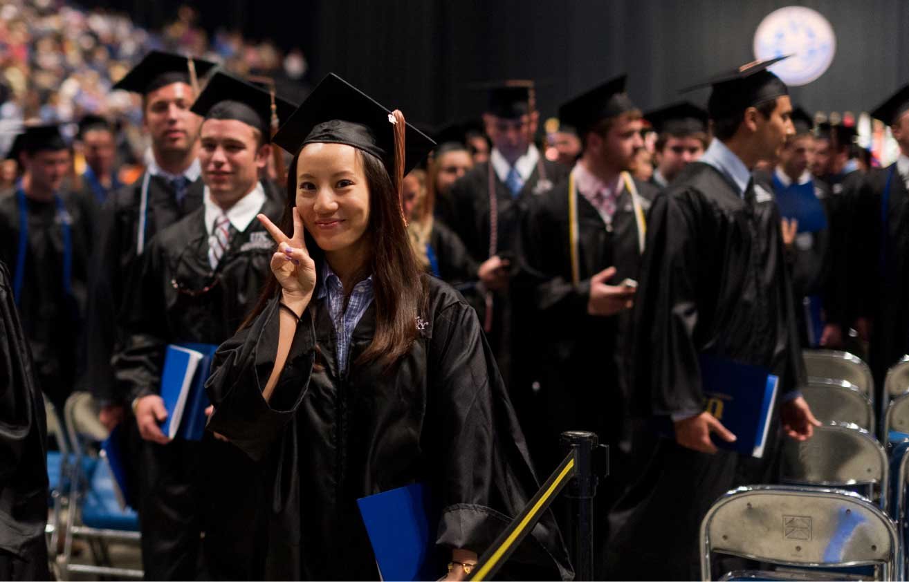 graduating young woman making peace sign